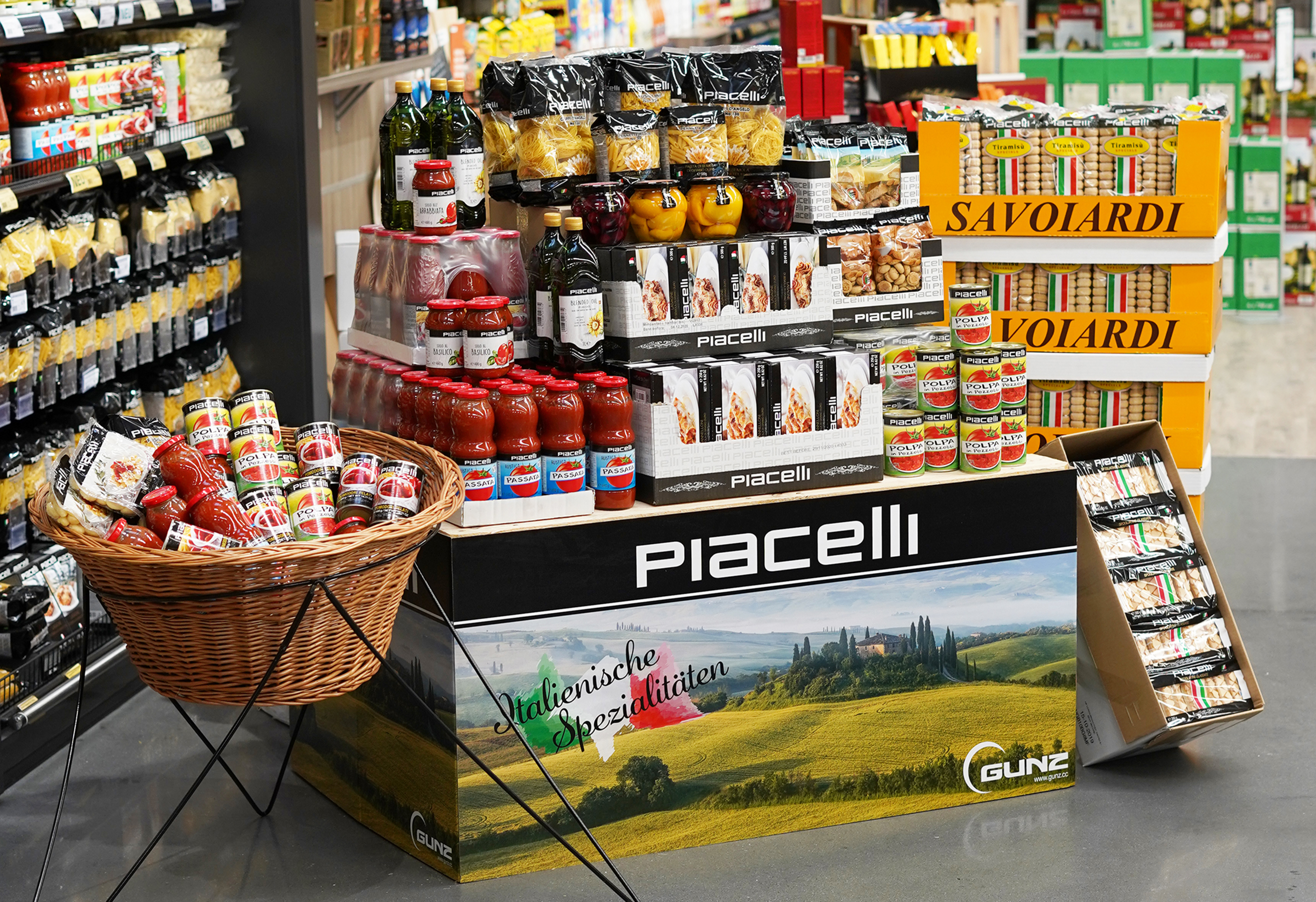 Présentoir dans un supermarché avec des produits italiens Piacelli comme des pâtes, de la sauce tomate, de l'huile d'olive et des pâtisseries.