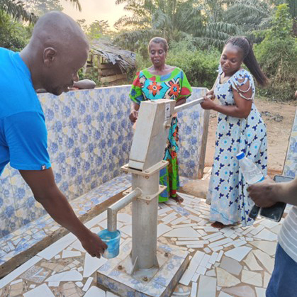 People pumping water at well