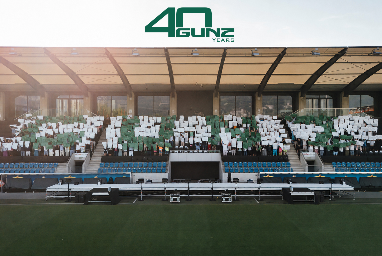 Gli ospiti formano la scritta "GUNZ" sulle tribune dello stadio durante il 40&deg; anniversario dell'azienda